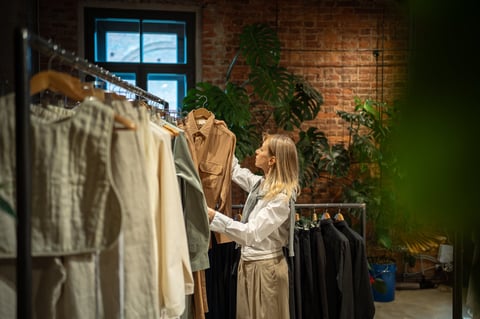 Interested woman stands in fashion store, carefully chooses clothes to buy